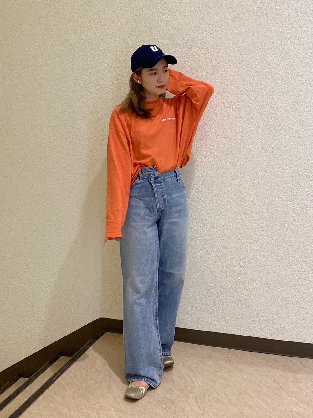 オレンジ系のTシャツ/カットソー、ブルー系のデニムパンツを着用したレディースの冬コーディネートの7枚目の写真