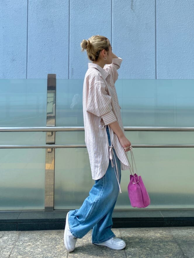 ピンク系のシャツ/ブラウス、ピンク系のハンドバッグ、ブルー系のデニムパンツを着用したレディースの春コーディネートの2枚目の写真