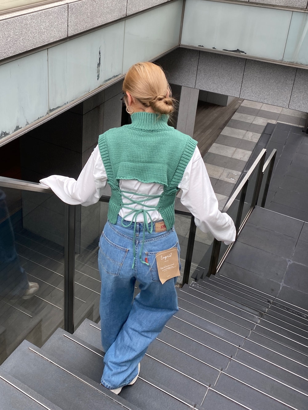 ブルー系のデニムパンツ、グリーン系のワンピースを着用したレディースの冬コーディネートの2枚目の写真