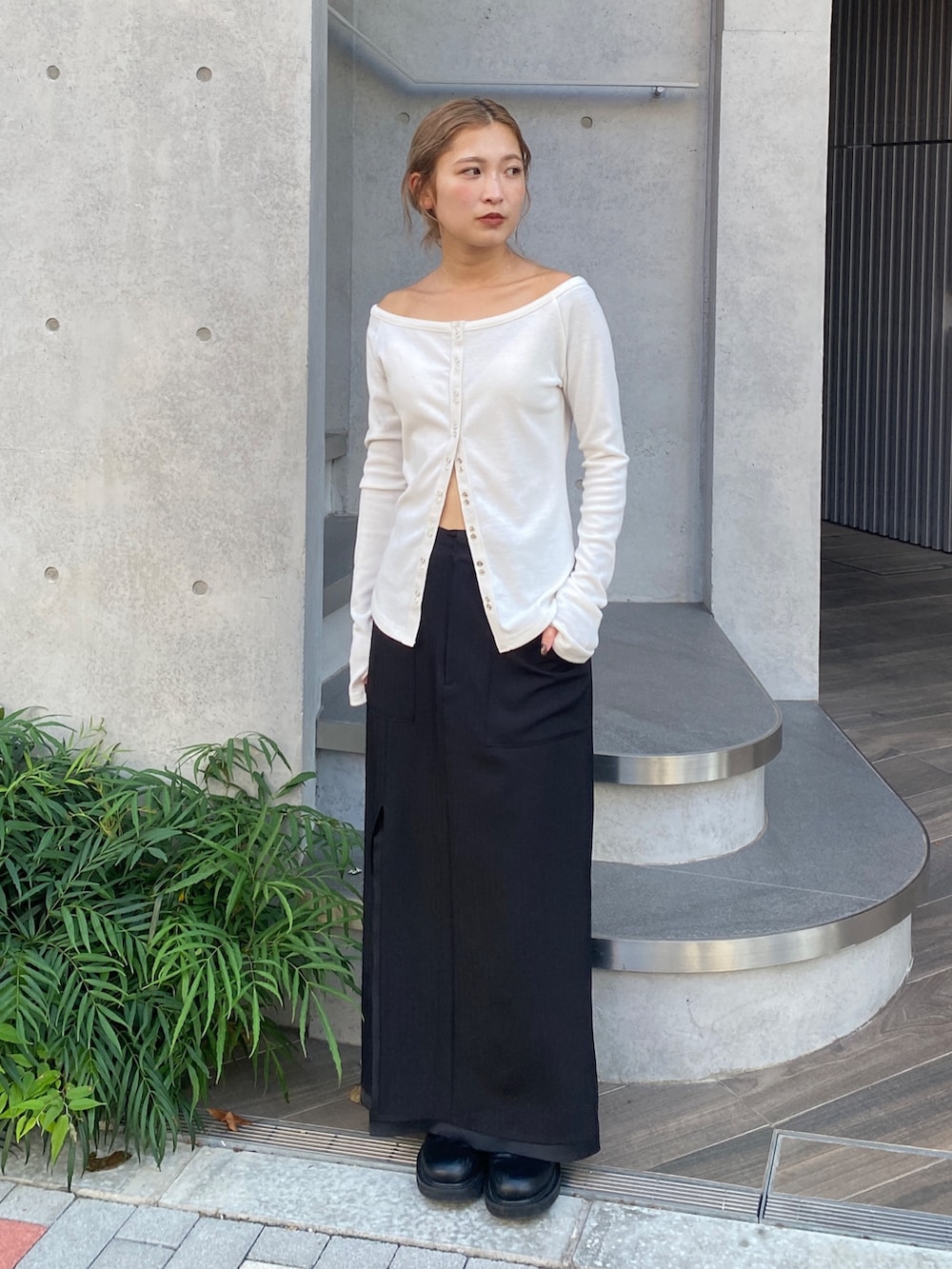 ホワイト系のTシャツ/カットソー、ブラック系のスカート、ブラック系のブーツを着用したレディースの秋コーディネートの4枚目の写真