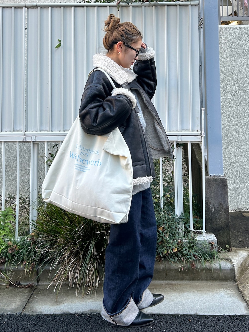 ブラック系のブルゾン、グレー系のカーディガン/ボレロ、ブルー系のデニムパンツを着用したレディースの冬コーディネートの2枚目の写真