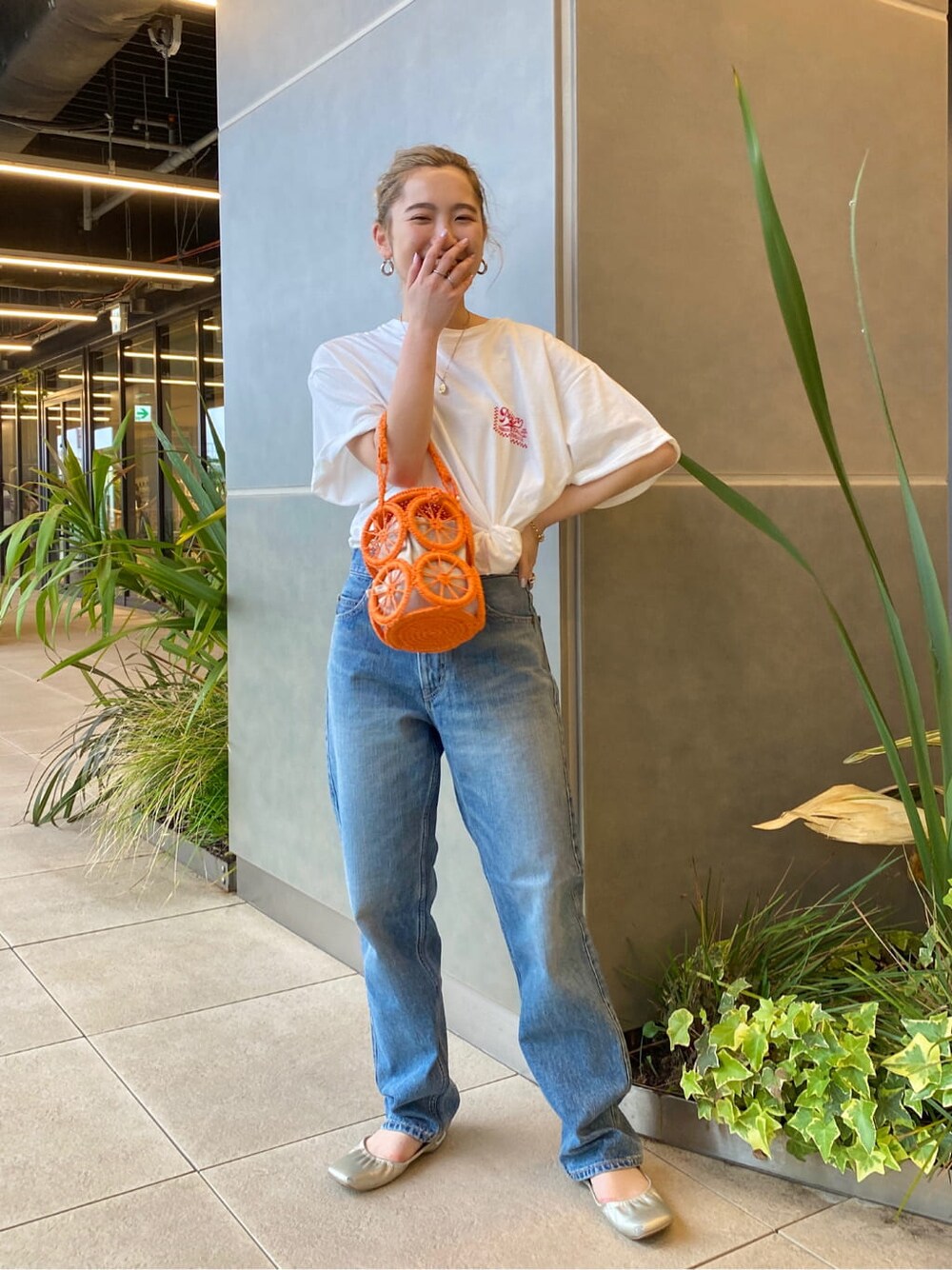 オレンジ系のかごバッグ、ホワイト系のTシャツ/カットソー、ブルー系のデニムパンツを着用したレディースの春コーディネートの3枚目の写真