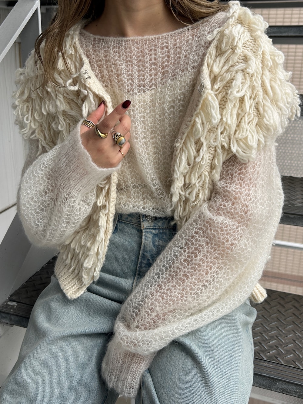 ホワイト系のベスト、ホワイト系のニット/セーター、ブルー系のデニムパンツを着用したレディースの秋コーディネートの3枚目の写真