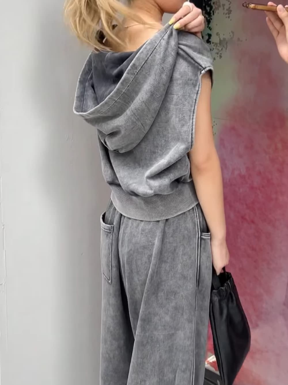 グレー系のパーカー、グレー系のスウェットパンツ、ブラック系のショルダーバッグを着用したレディースの夏コーディネートの2枚目の写真