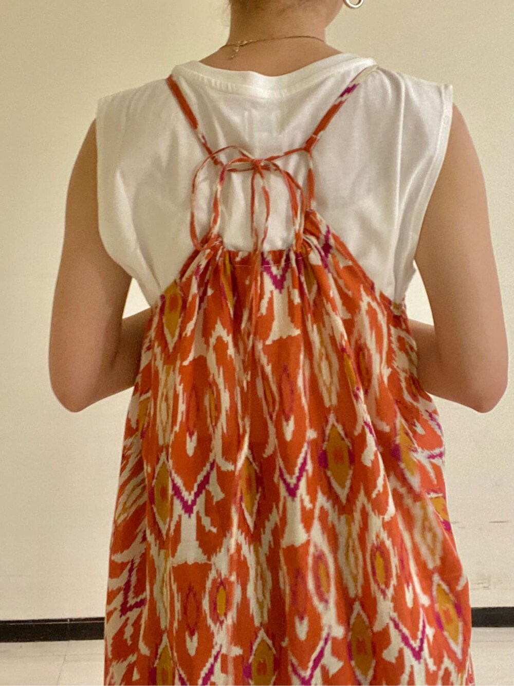 ホワイト系のタンクトップ、オレンジ系のワンピース、ブルー系のデニムパンツを着用したレディースの春コーディネートの4枚目の写真