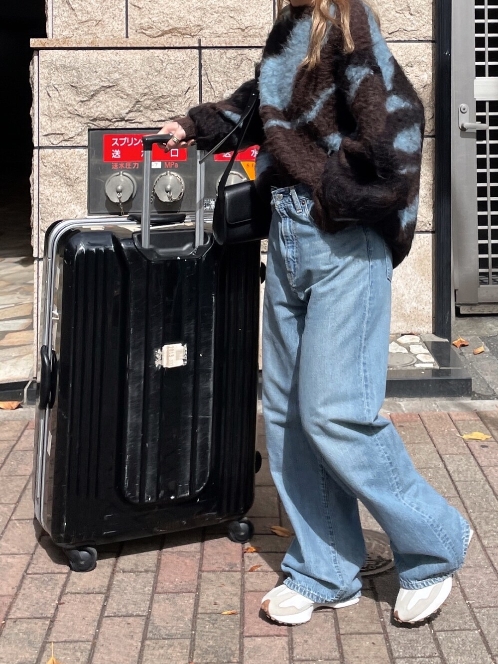 ブラウン系のニット/セーター、ブルー系のデニムパンツ、ブラック系のメガネを着用したレディースの秋コーディネートの9枚目の写真