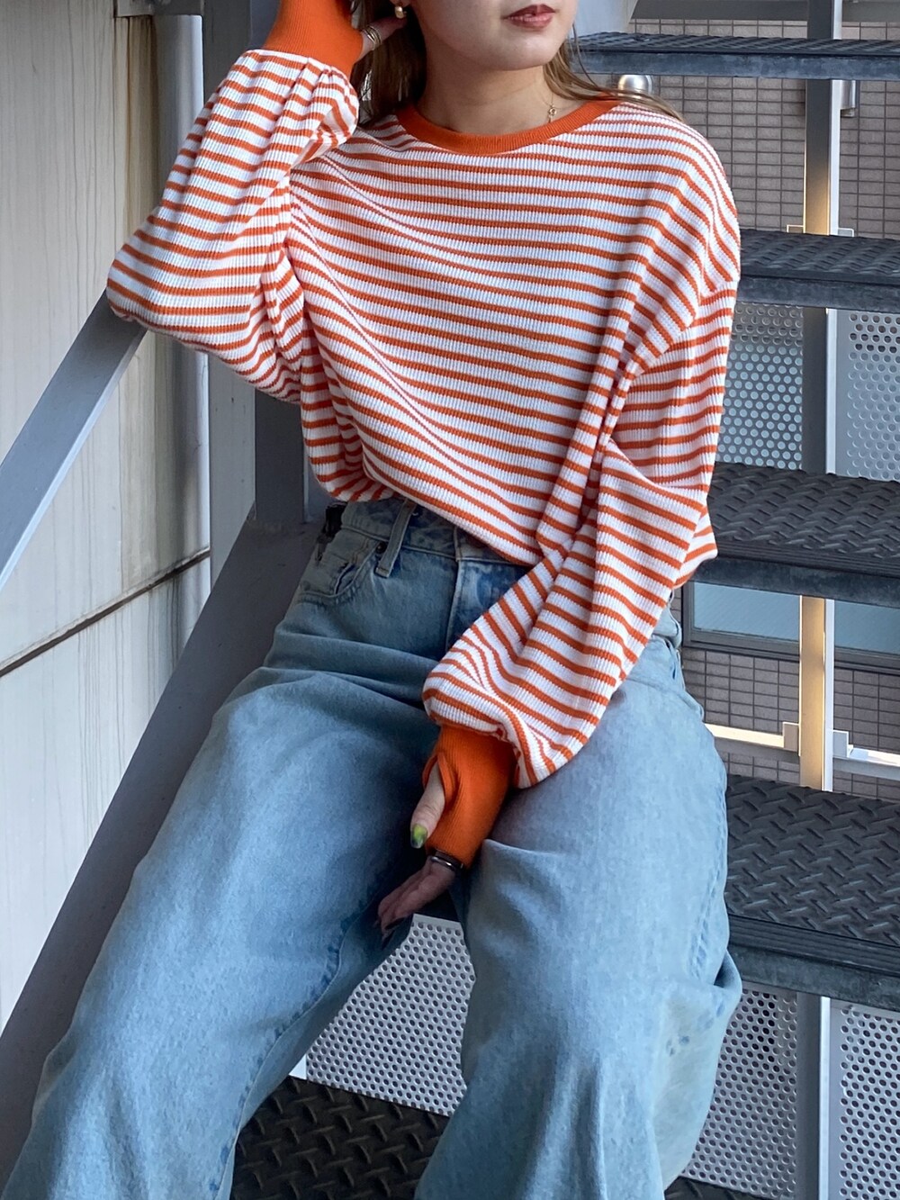 オレンジ系のTシャツ/カットソー、ブルー系のデニムパンツを着用したレディースの冬コーディネートの2枚目の写真