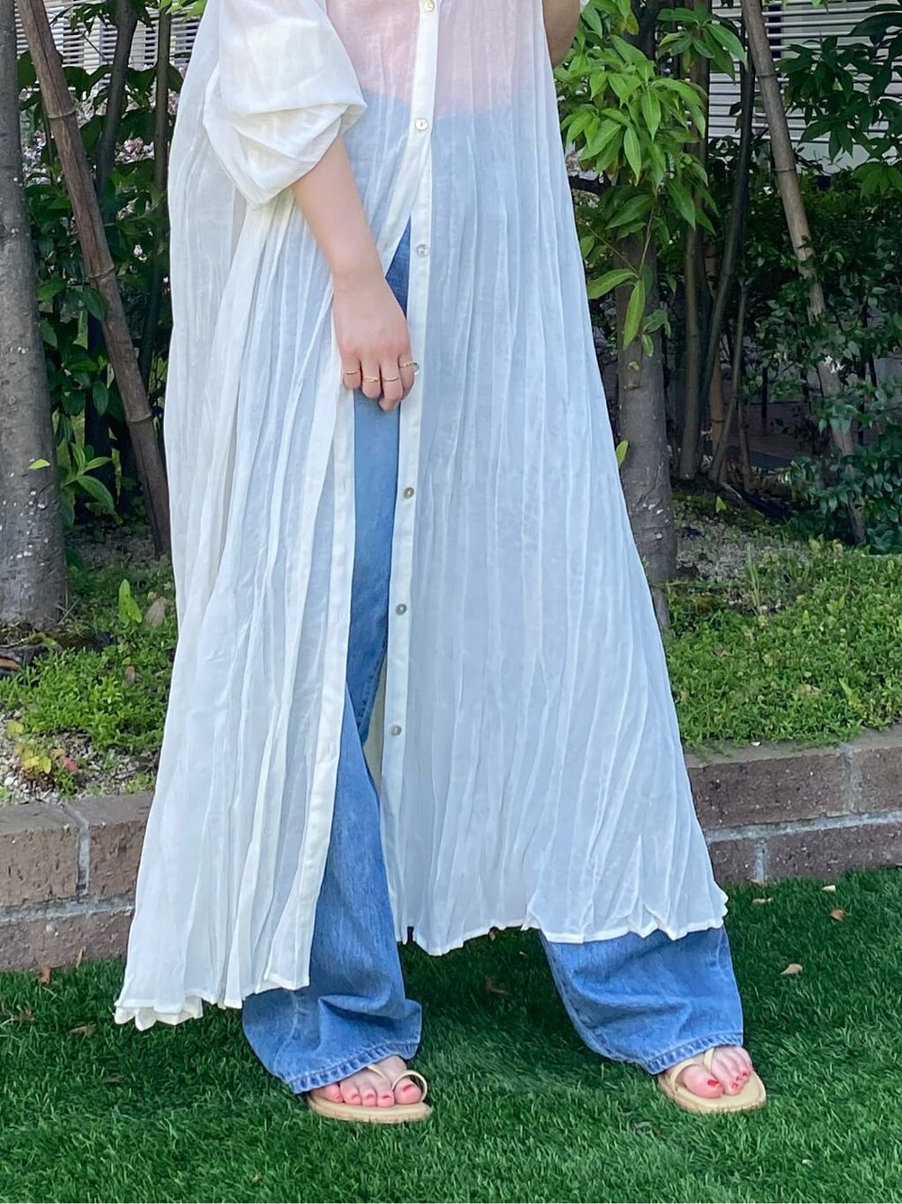 グリーン系のサンダル、ブルー系のデニムパンツ、ホワイト系のスニーカーを着用したレディースの夏コーディネートの6枚目の写真