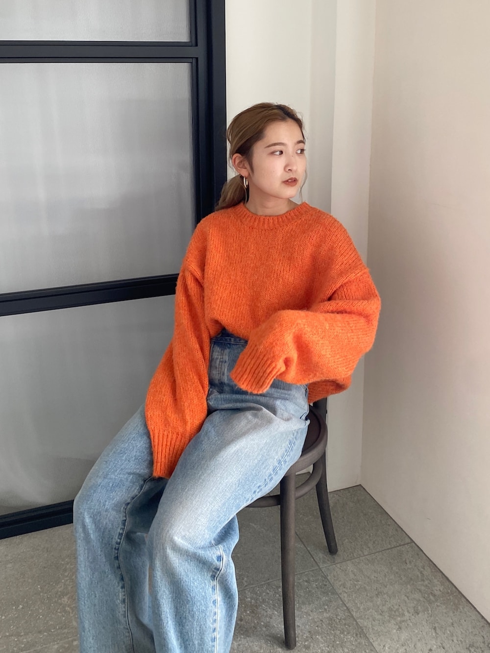 オレンジ系のニット/セーター、ブルー系のデニムパンツを着用したレディースの冬コーディネートの10枚目の写真