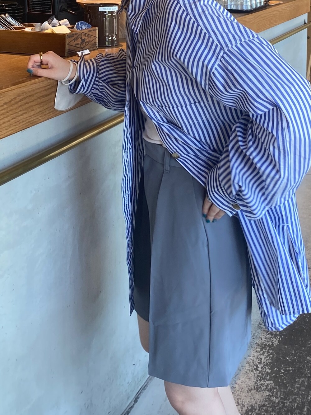 ブルー系のシャツ/ブラウス、グレー系のパンツ、ブラック系のサングラスを着用したレディースの夏コーディネートの2枚目の写真