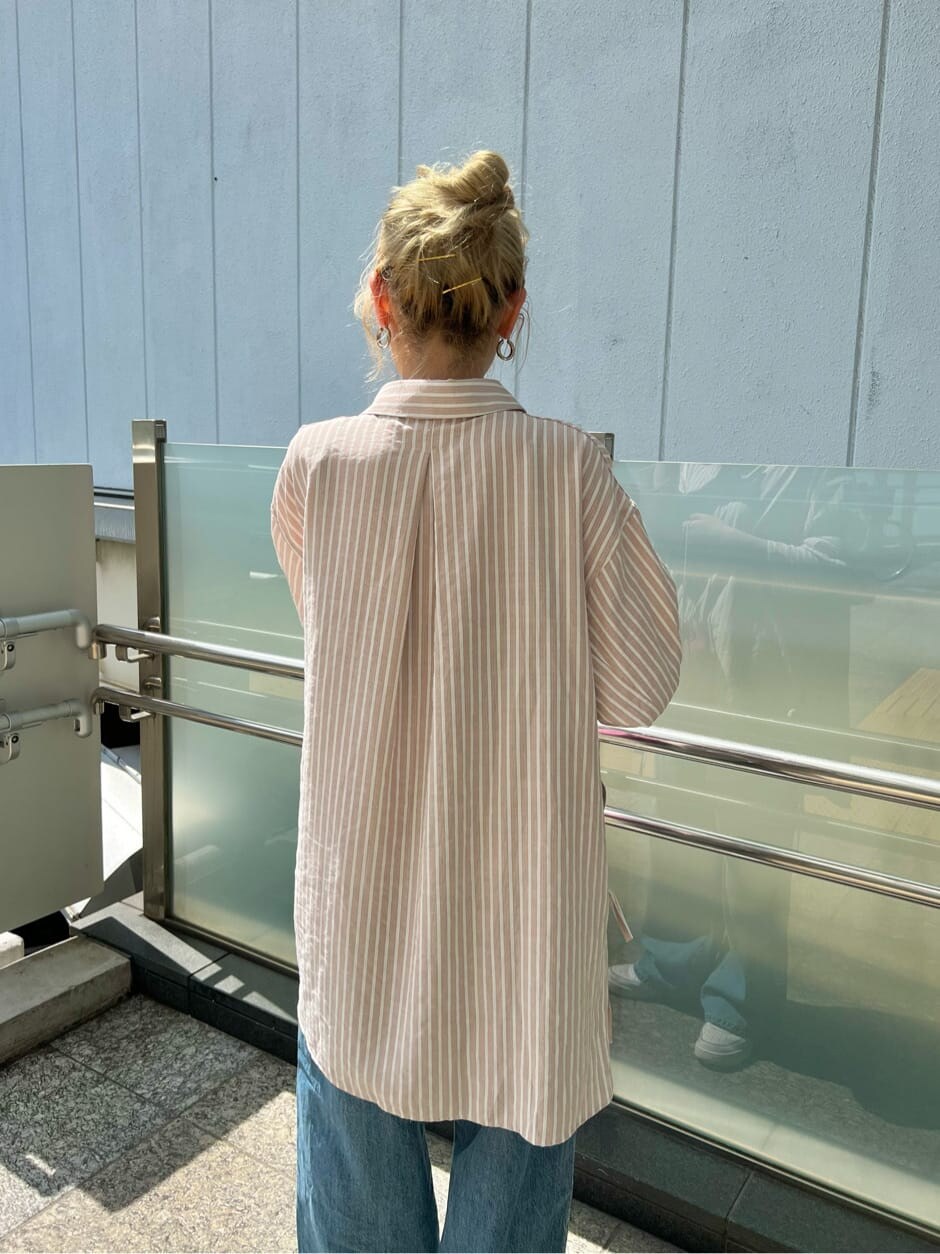 ピンク系のシャツ/ブラウス、ピンク系のハンドバッグ、ブルー系のデニムパンツを着用したレディースの春コーディネートの5枚目の写真