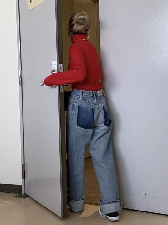 レッド系のニット/セーター、ブラック系のショルダーバッグ、ブルー系のデニムパンツを着用したレディースの夏コーディネートの3枚目の写真