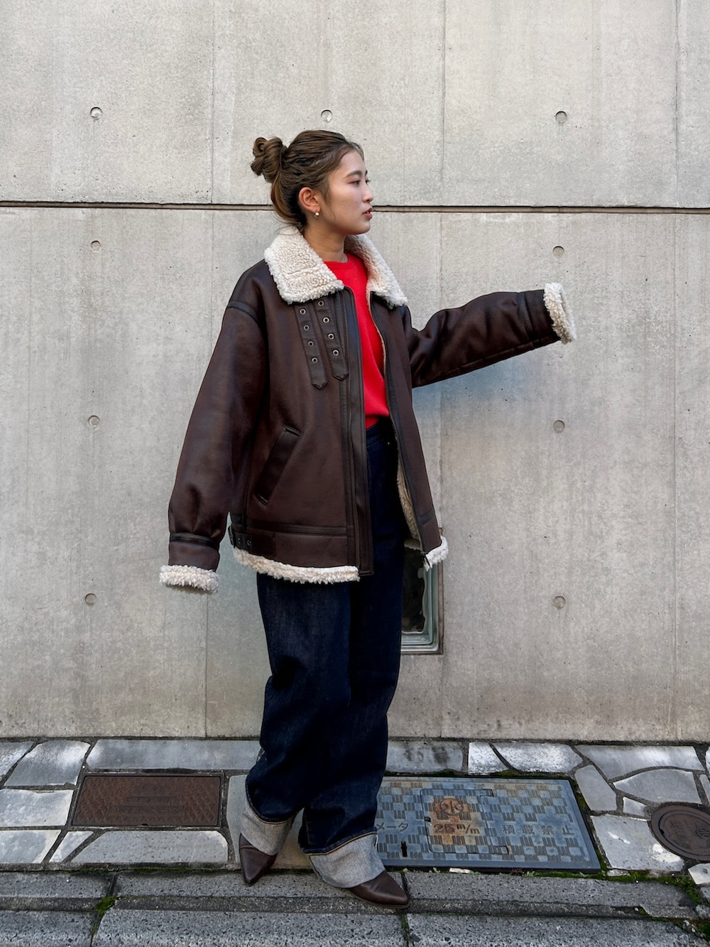レッド系のニット/セーター、ブラウン系のブルゾン、ブルー系のデニムパンツを着用したレディースの冬コーディネートの2枚目の写真