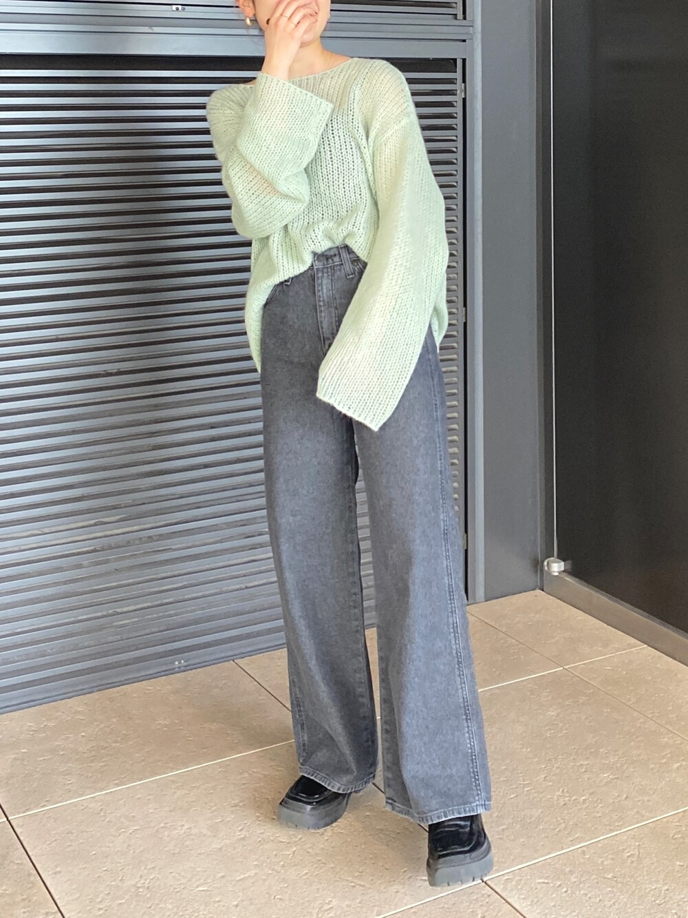 グリーン系のニット/セーター、ブラック系のデニムパンツを着用したレディースの冬コーディネートの2枚目の写真