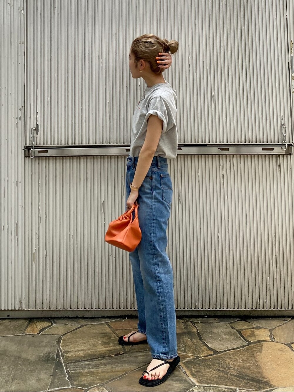 ブルー系のデニムパンツ、ブラック系のサンダル、グレー系のTシャツ/カットソーを着用したレディースの夏コーディネートの3枚目の写真