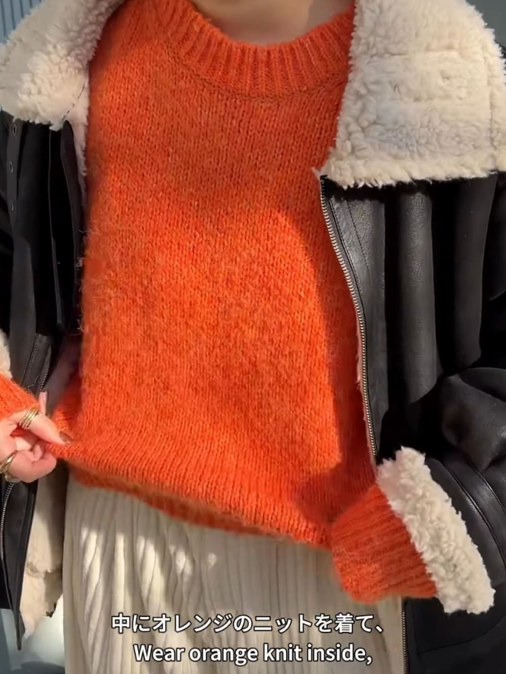 オレンジ系のニット/セーター、ブラック系のブルゾン、ホワイト系のその他パンツを着用したレディースの冬コーディネートの3枚目の写真
