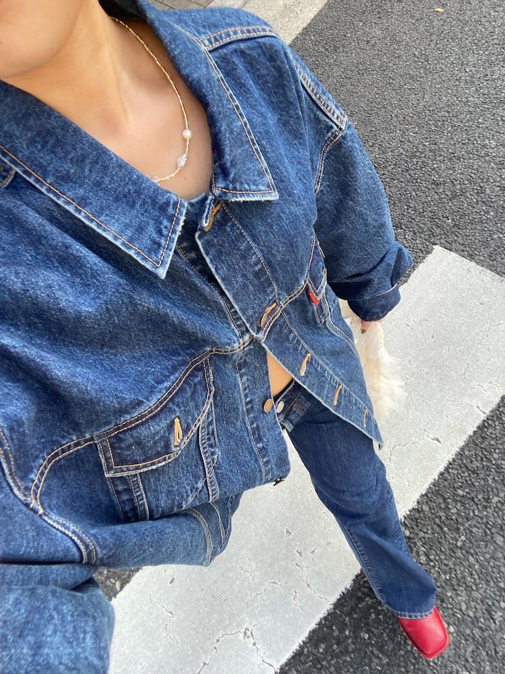 ブルー系のデニムジャケット、ブルー系のデニムパンツ、ホワイト系のショルダーバッグを着用したレディースの夏コーディネートの5枚目の写真