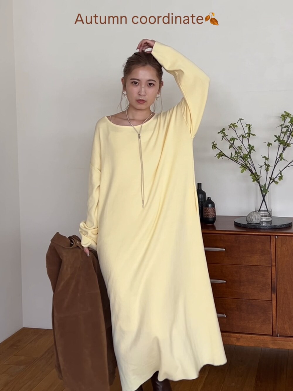 ブラウン系のブルゾン、イエロー系のワンピース、ホワイト系のネックレスを着用したレディースの秋コーディネートの3枚目の写真