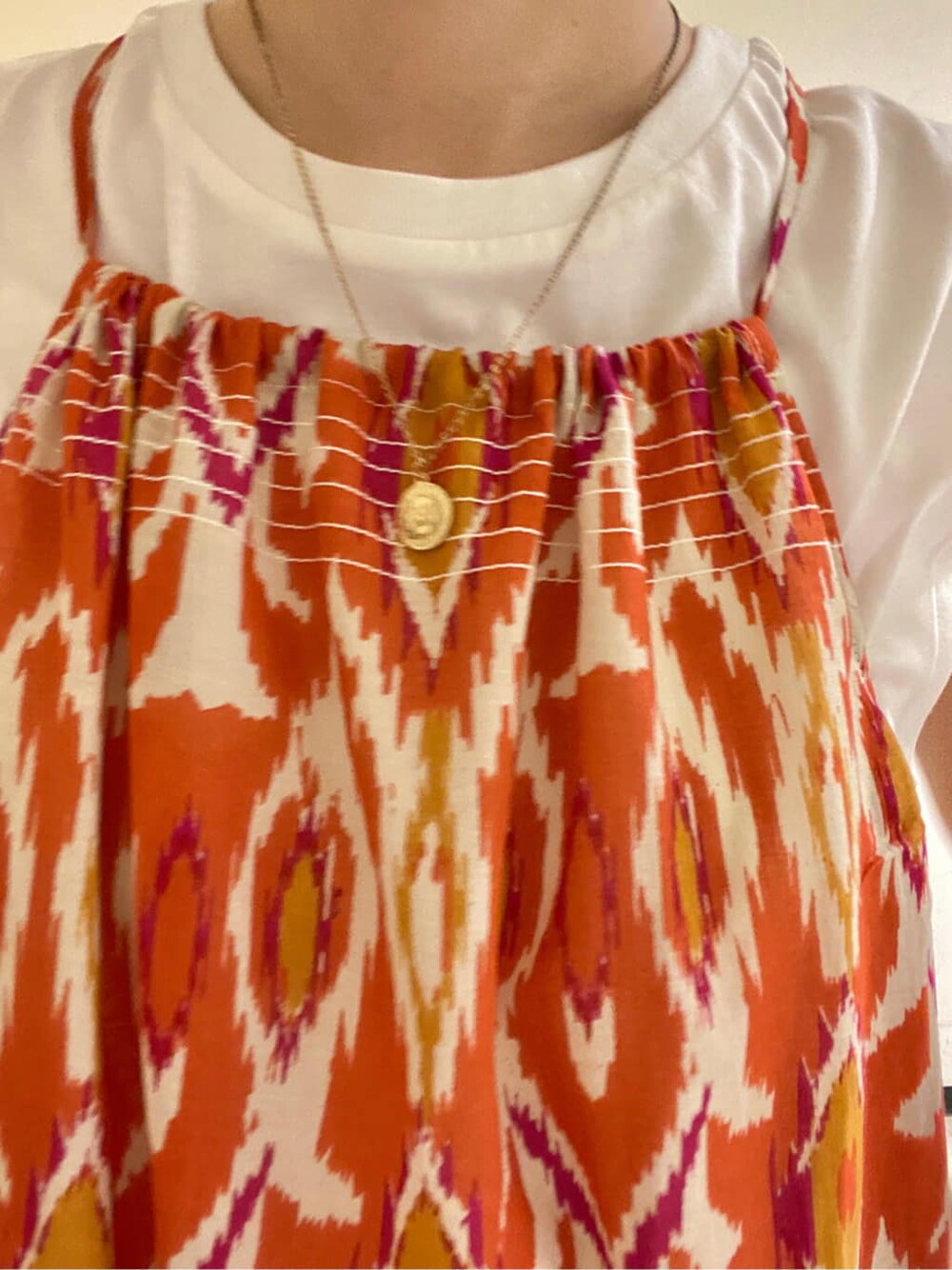 ホワイト系のタンクトップ、オレンジ系のワンピース、ブルー系のデニムパンツを着用したレディースの春コーディネートの3枚目の写真