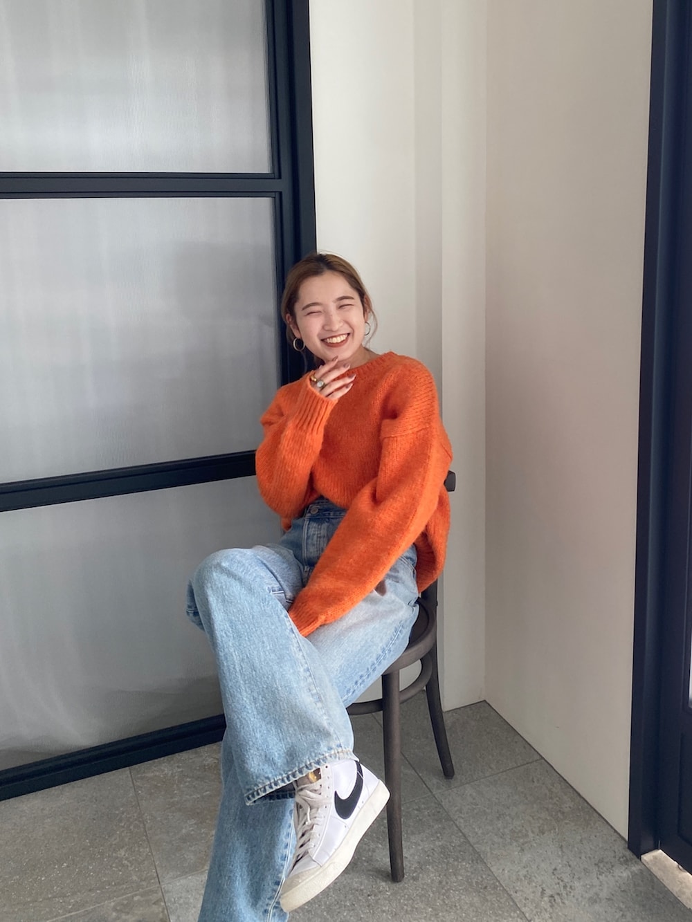 オレンジ系のニット/セーター、ブルー系のデニムパンツを着用したレディースの冬コーディネートの5枚目の写真