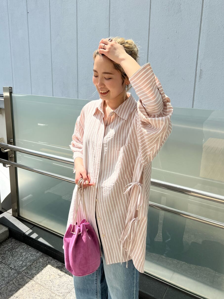 ピンク系のシャツ/ブラウス、ピンク系のハンドバッグ、ブルー系のデニムパンツを着用したレディースの春コーディネートの4枚目の写真