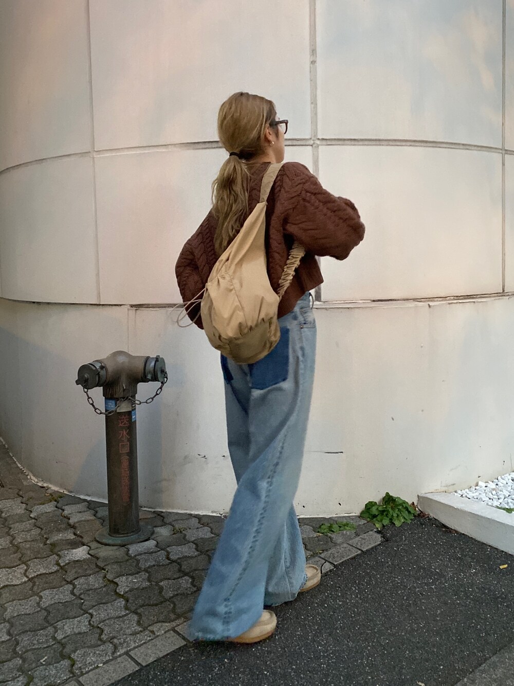 ブラウン系のニット/セーター、ブルー系のデニムパンツ、ベージュ系のハンドバッグを着用したレディースの冬コーディネートの8枚目の写真