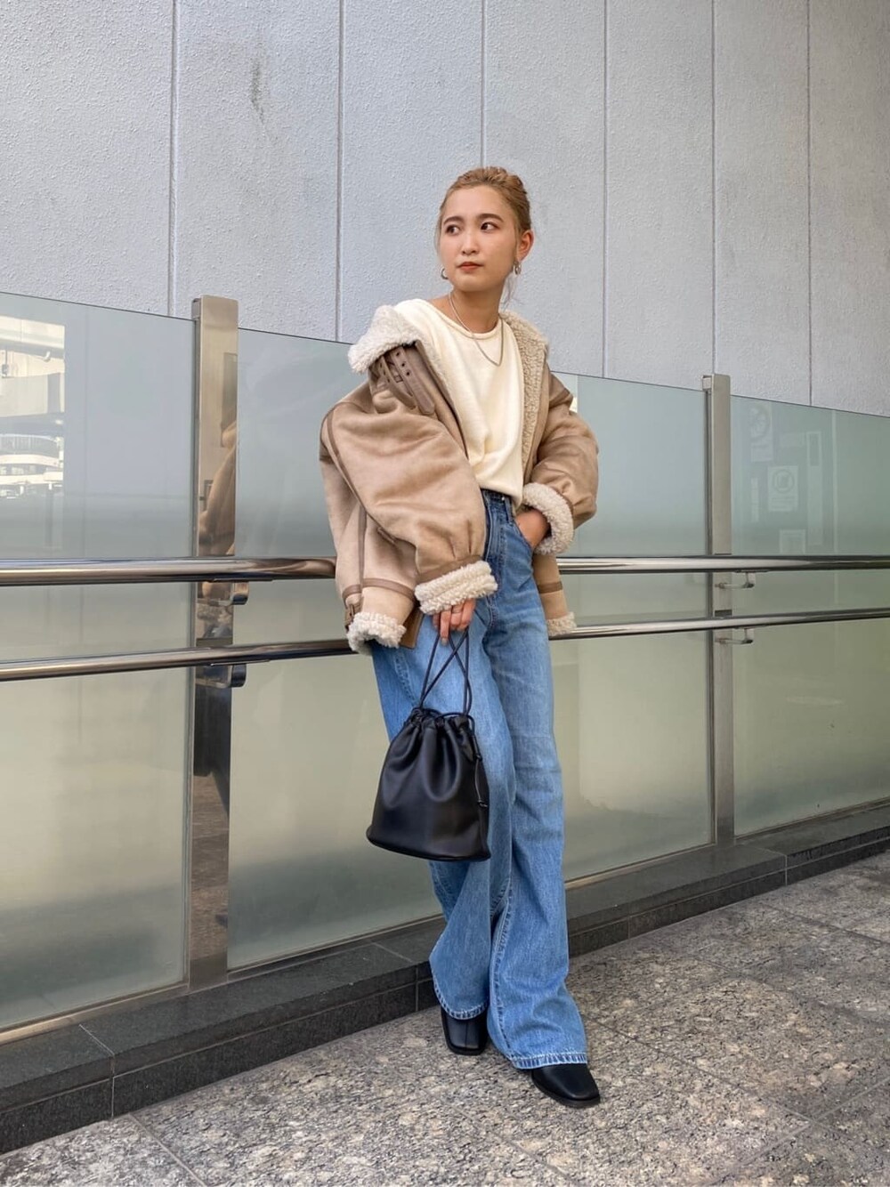 ブルー系のデニムパンツ、ブラック系のブーツ、ブラック系のハンドバッグを着用したレディースの秋コーディネートの3枚目の写真