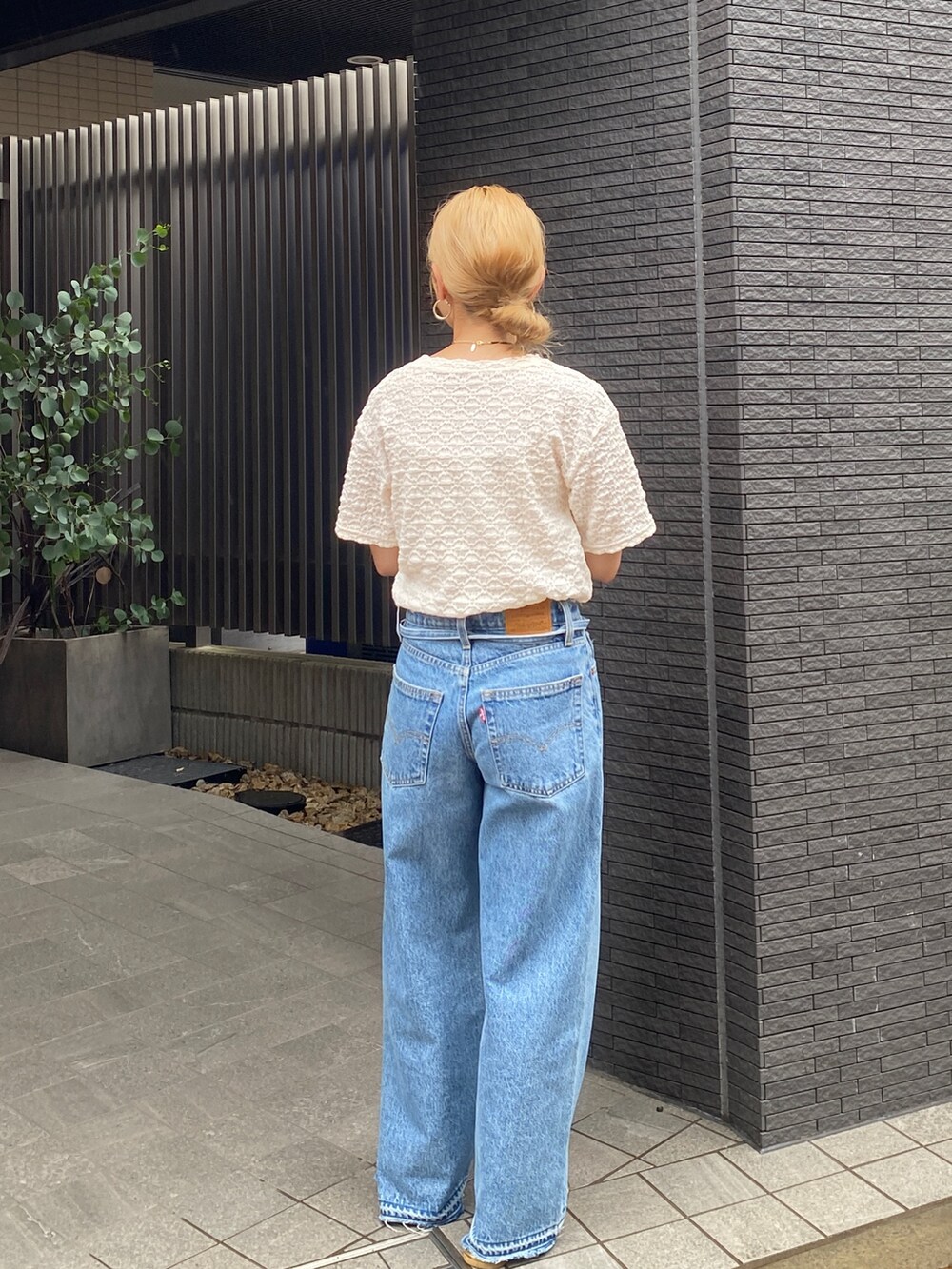 ブルー系のデニムパンツ、ホワイト系のTシャツ/カットソー、ゴールド系のローファーを着用したレディースの夏コーディネートの2枚目の写真