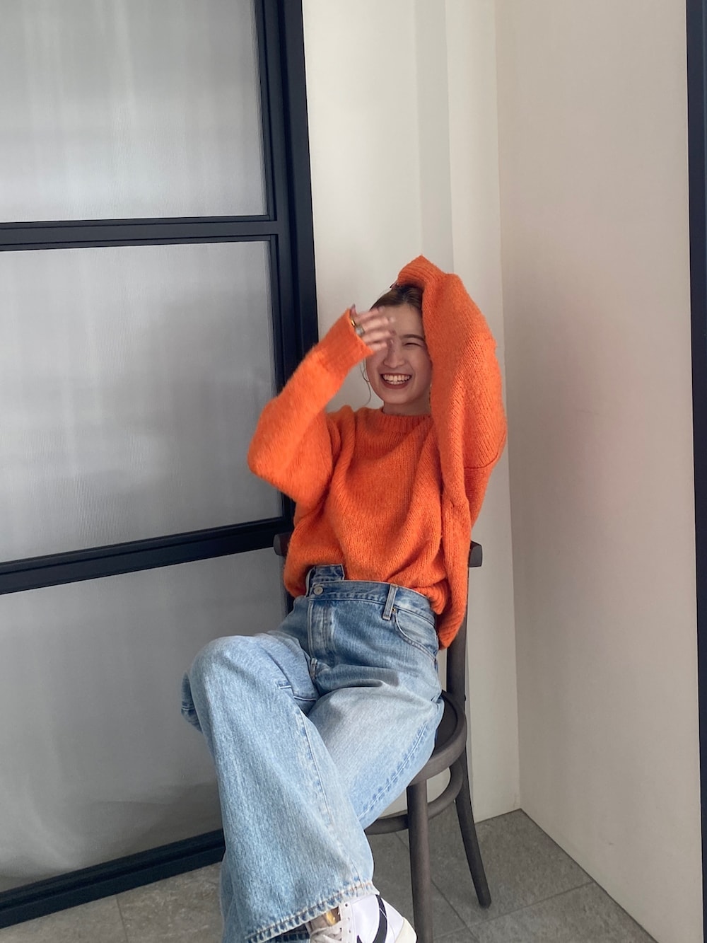 オレンジ系のニット/セーター、ブルー系のデニムパンツを着用したレディースの冬コーディネートの4枚目の写真