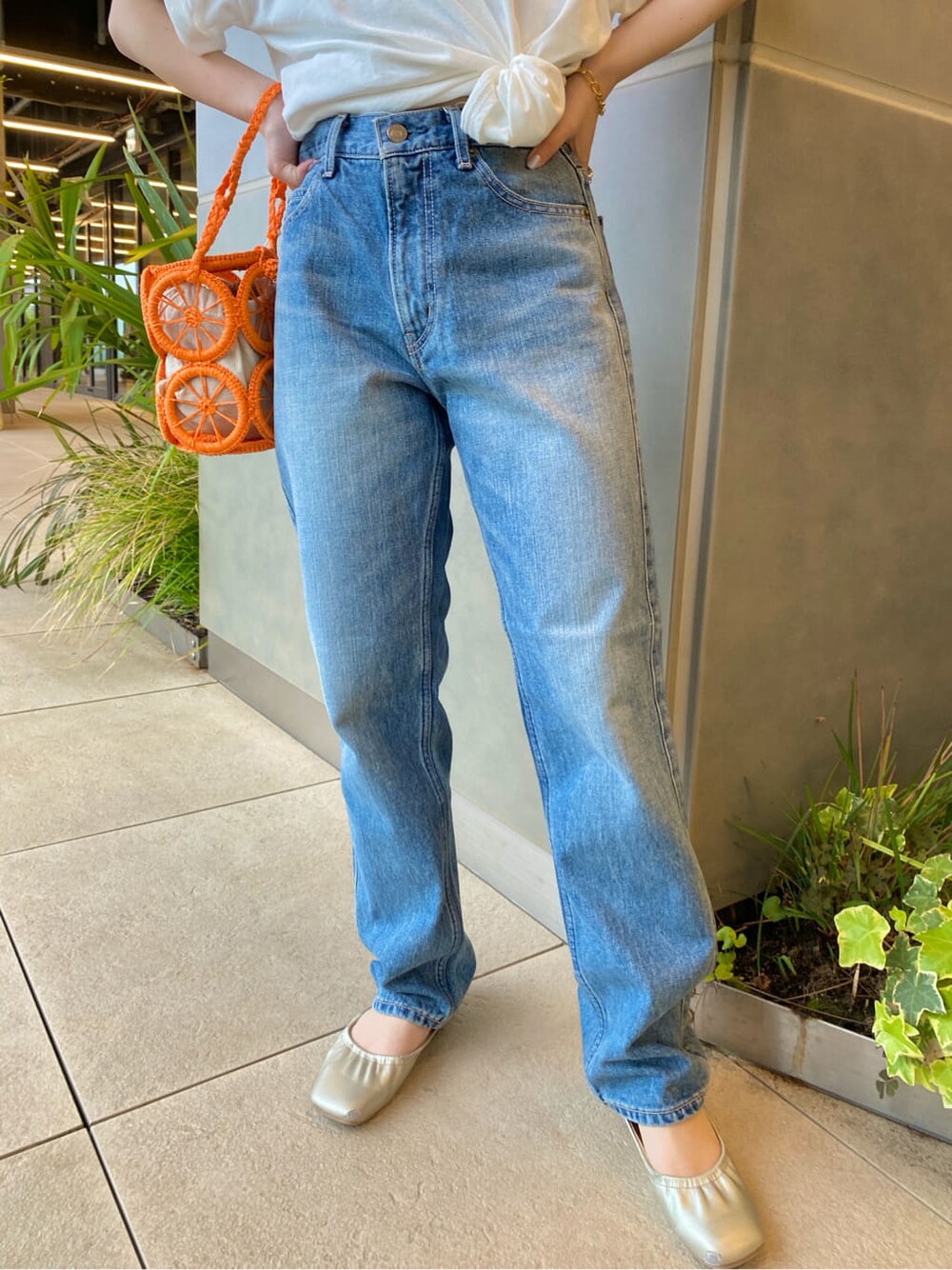 オレンジ系のかごバッグ、ホワイト系のTシャツ/カットソー、ブルー系のデニムパンツを着用したレディースの春コーディネートの5枚目の写真