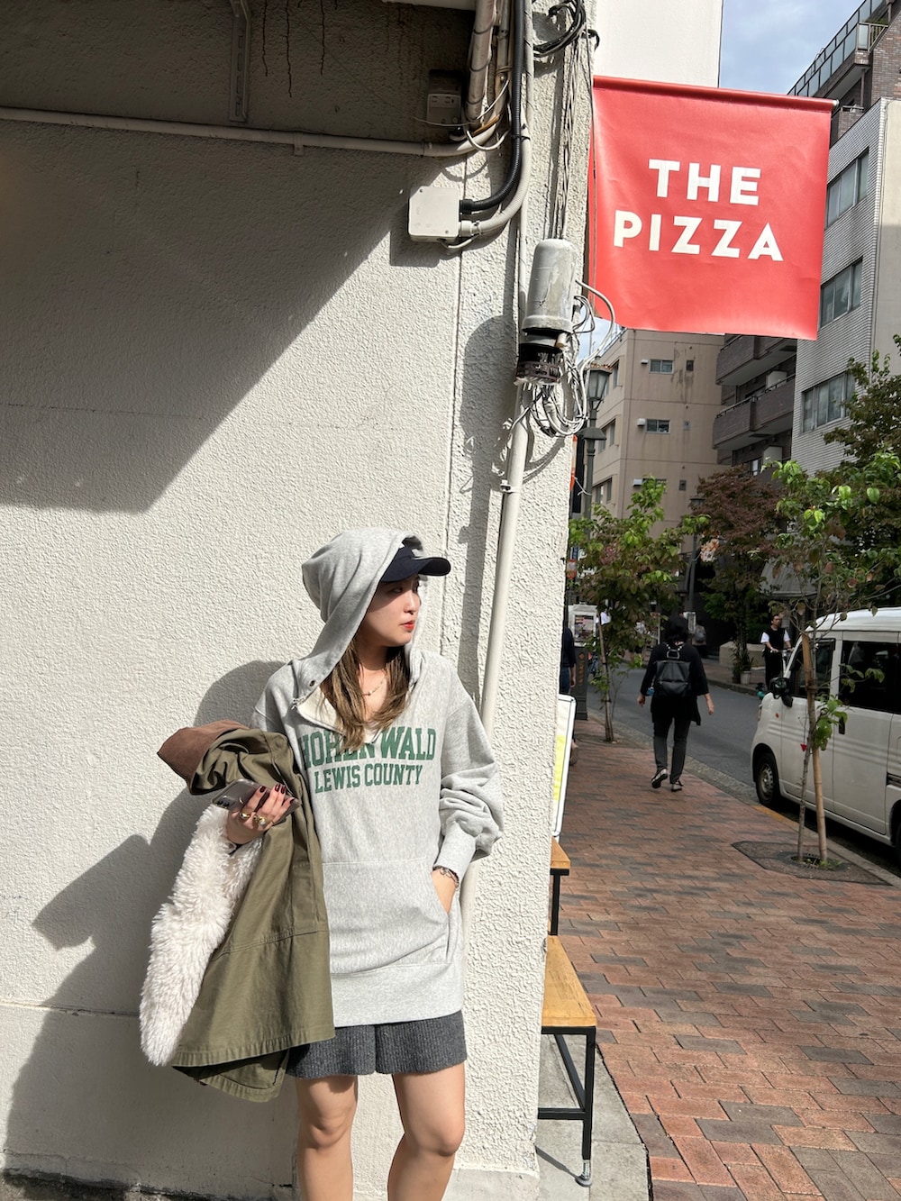 グレー系のパーカー、ホワイト系のハンドバッグ、ベージュ系のカバーオールを着用したレディースの冬コーディネートの2枚目の写真