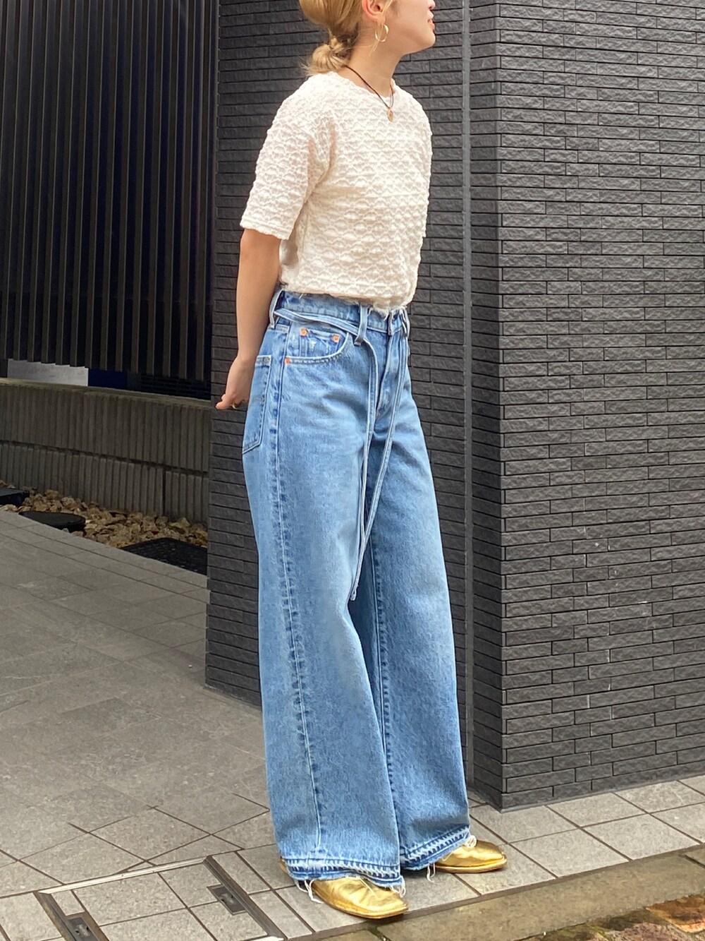 ブルー系のデニムパンツ、ホワイト系のTシャツ/カットソー、ゴールド系のローファーを着用したレディースの夏コーディネートの3枚目の写真