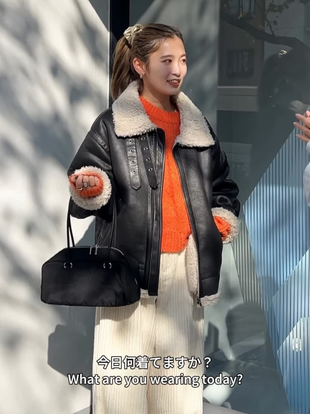 オレンジ系のニット/セーター、ブラック系のブルゾン、ホワイト系のその他パンツを着用したレディースの冬コーディネートの2枚目の写真