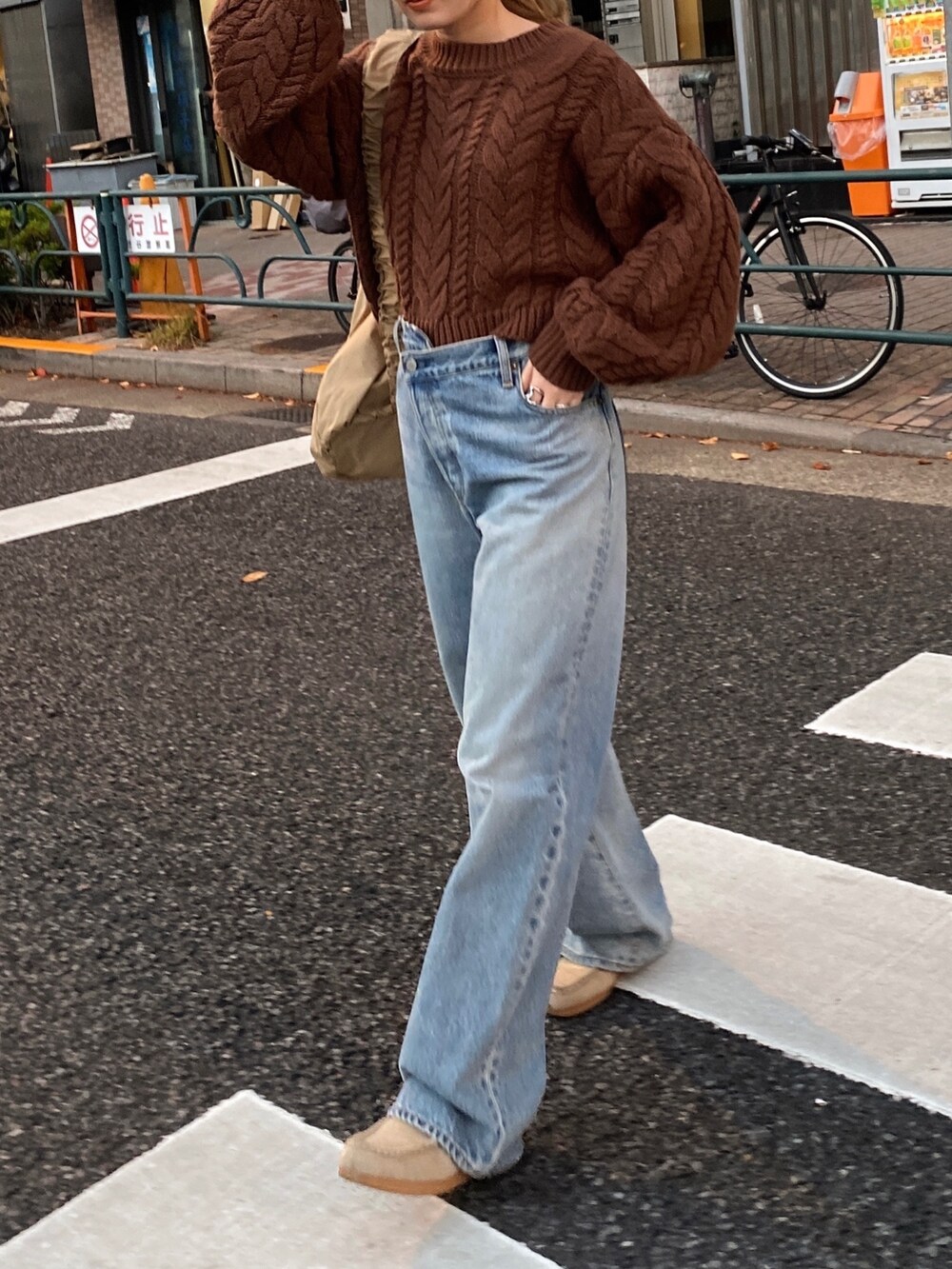 ブラウン系のニット/セーター、ブルー系のデニムパンツ、ベージュ系のハンドバッグを着用したレディースの冬コーディネートの4枚目の写真