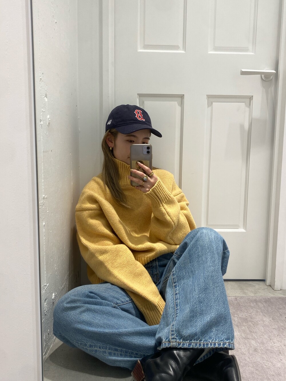 イエロー系のニット/セーター、ブルー系のデニムパンツ、ブラック系のブーツを着用したレディースの冬コーディネートの2枚目の写真