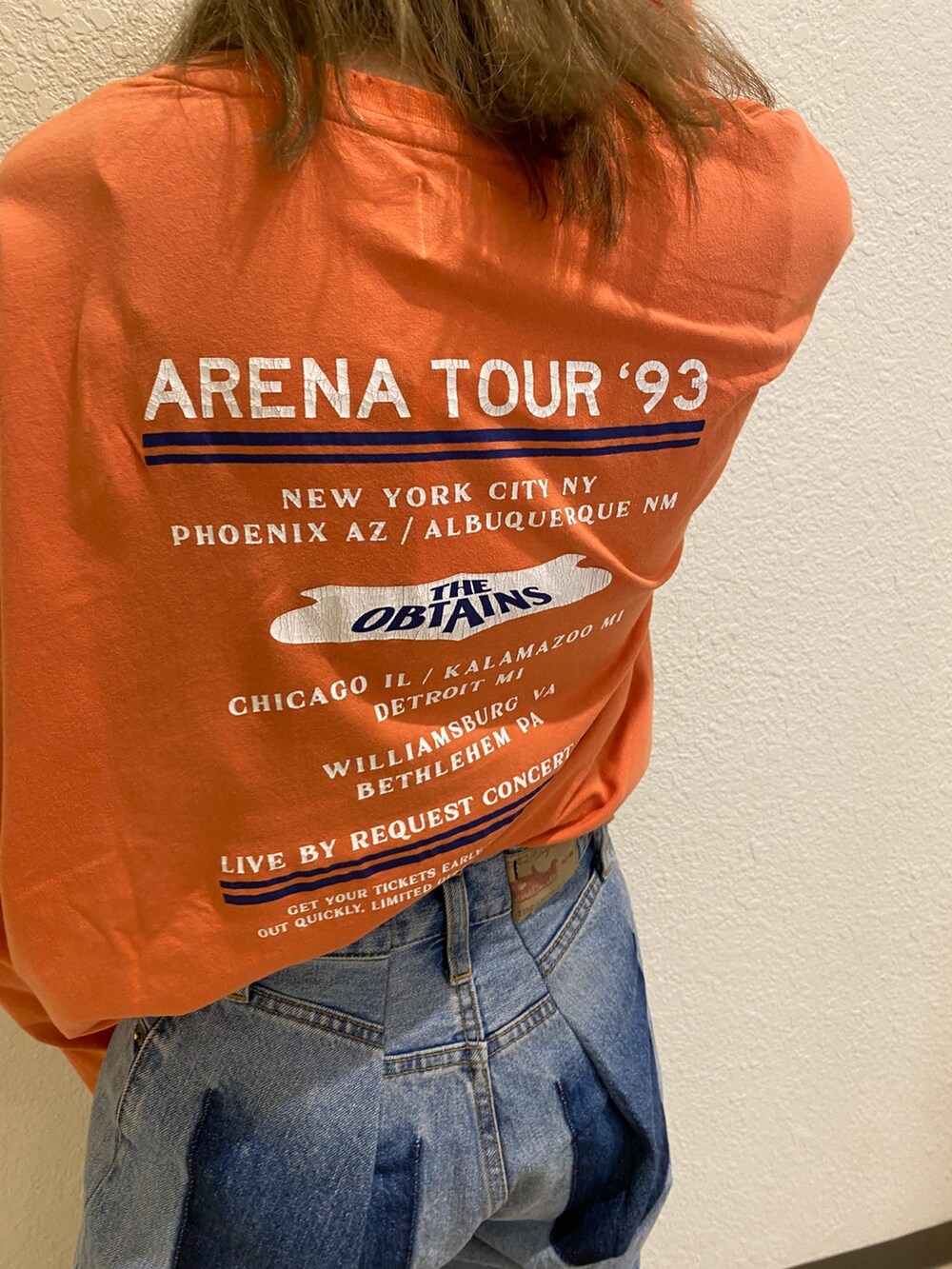 オレンジ系のTシャツ/カットソー、ブルー系のデニムパンツを着用したレディースの冬コーディネートの4枚目の写真
