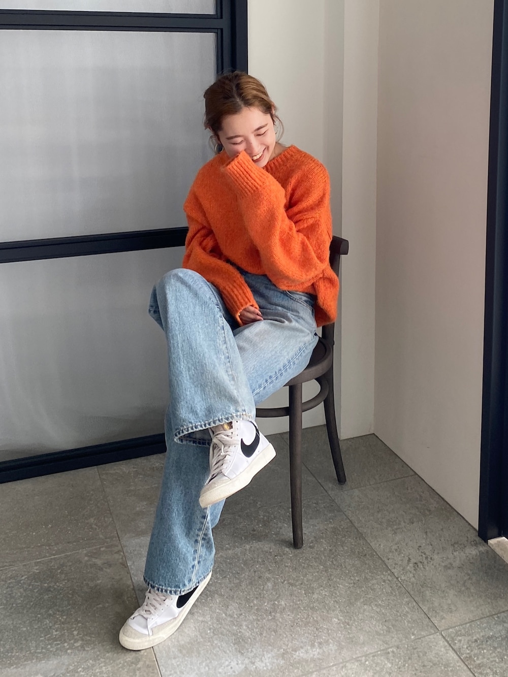 オレンジ系のニット/セーター、ブルー系のデニムパンツを着用したレディースの冬コーディネートの6枚目の写真
