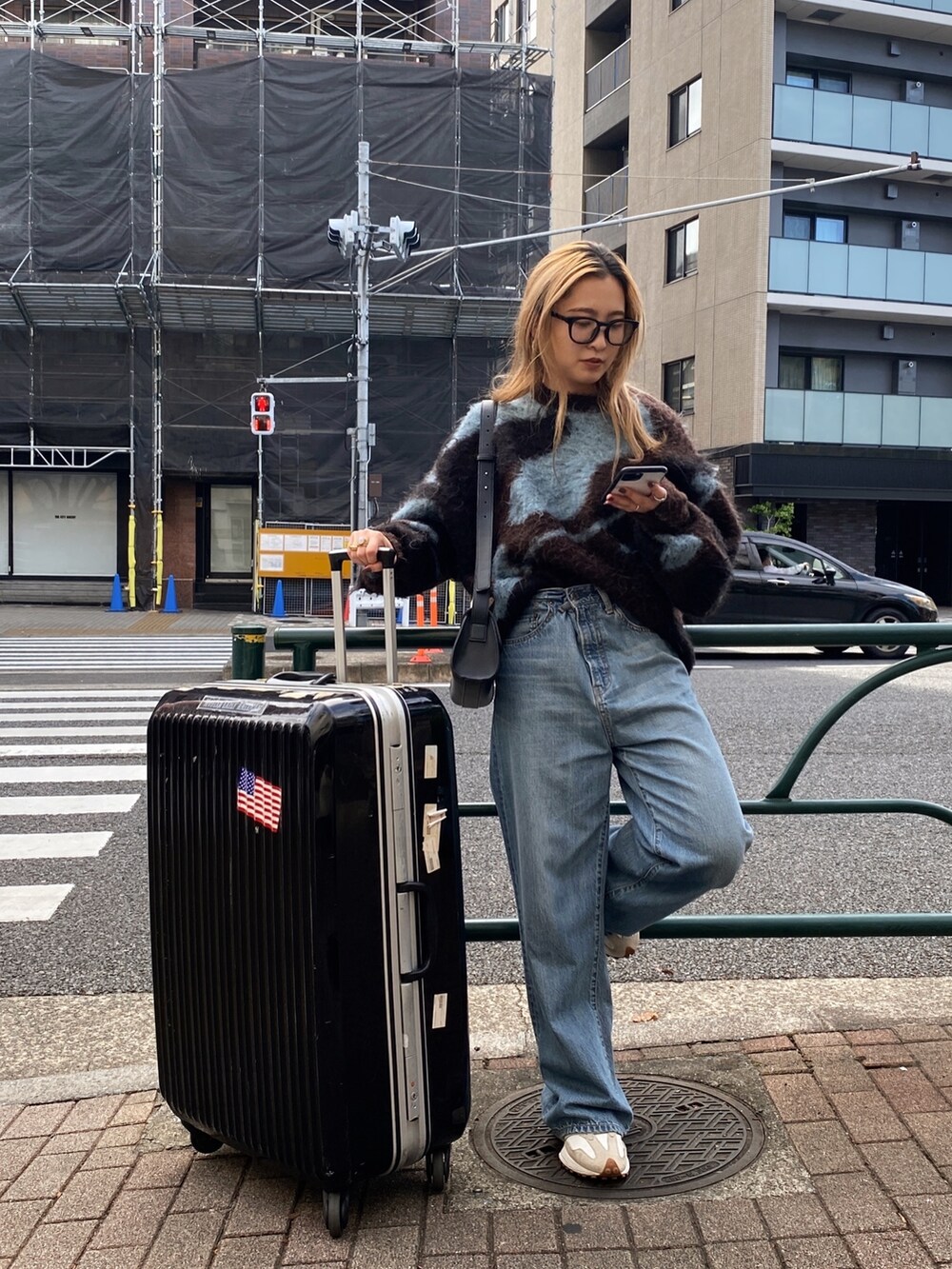 ブラウン系のニット/セーター、ブルー系のデニムパンツ、ブラック系のメガネを着用したレディースの秋コーディネートの5枚目の写真