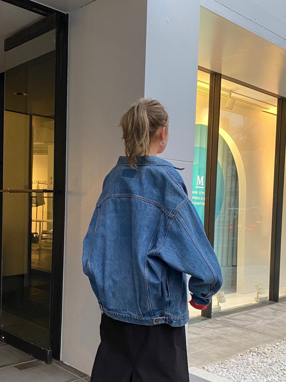 ブルー系のデニムジャケット、レッド系のスウェット、ブラック系のスカートを着用したレディースの冬コーディネートの4枚目の写真