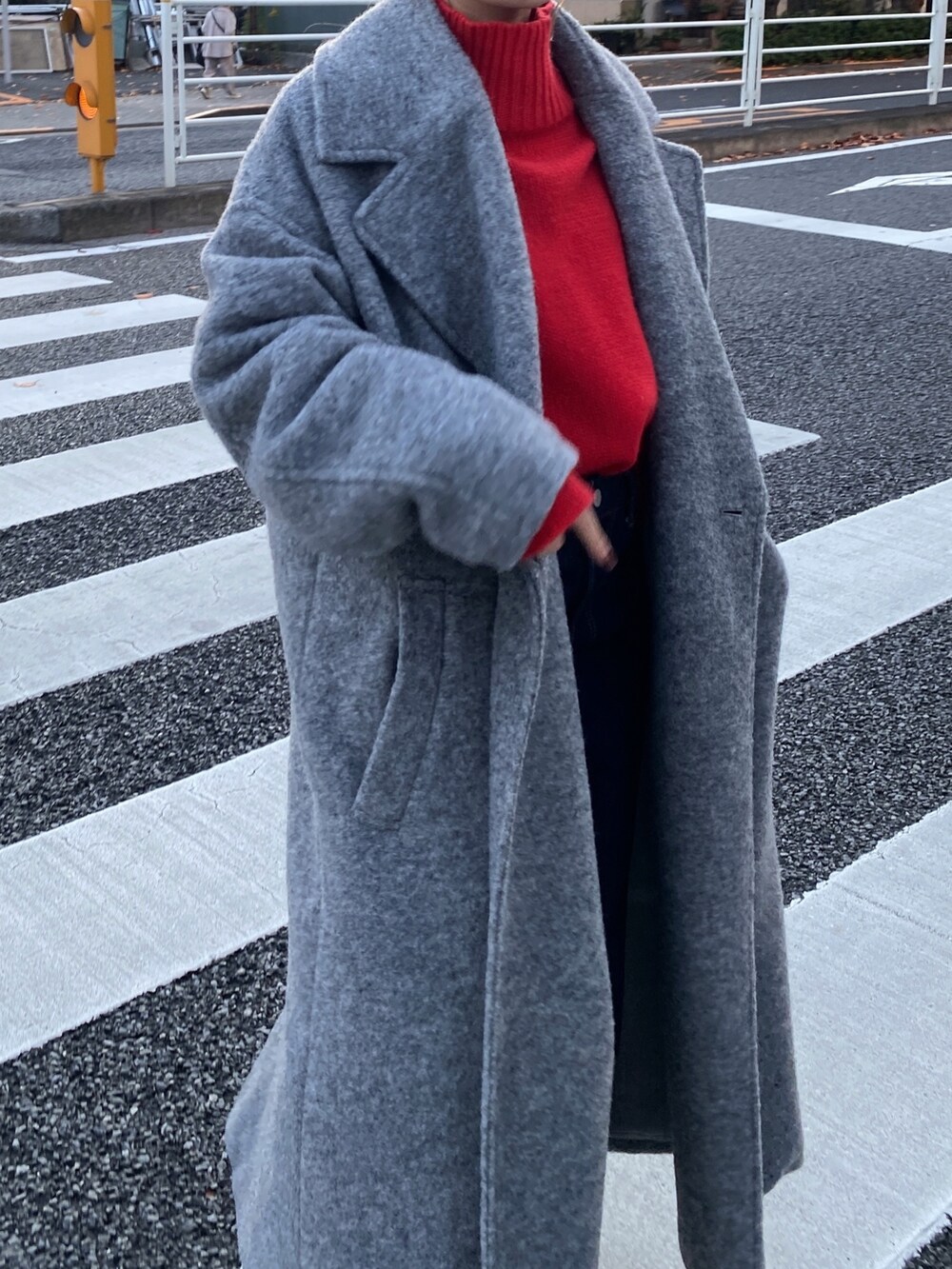 レッド系のニット/セーター、グレー系のチェスターコート、ブルー系のデニムパンツを着用したレディースの冬コーディネートの5枚目の写真