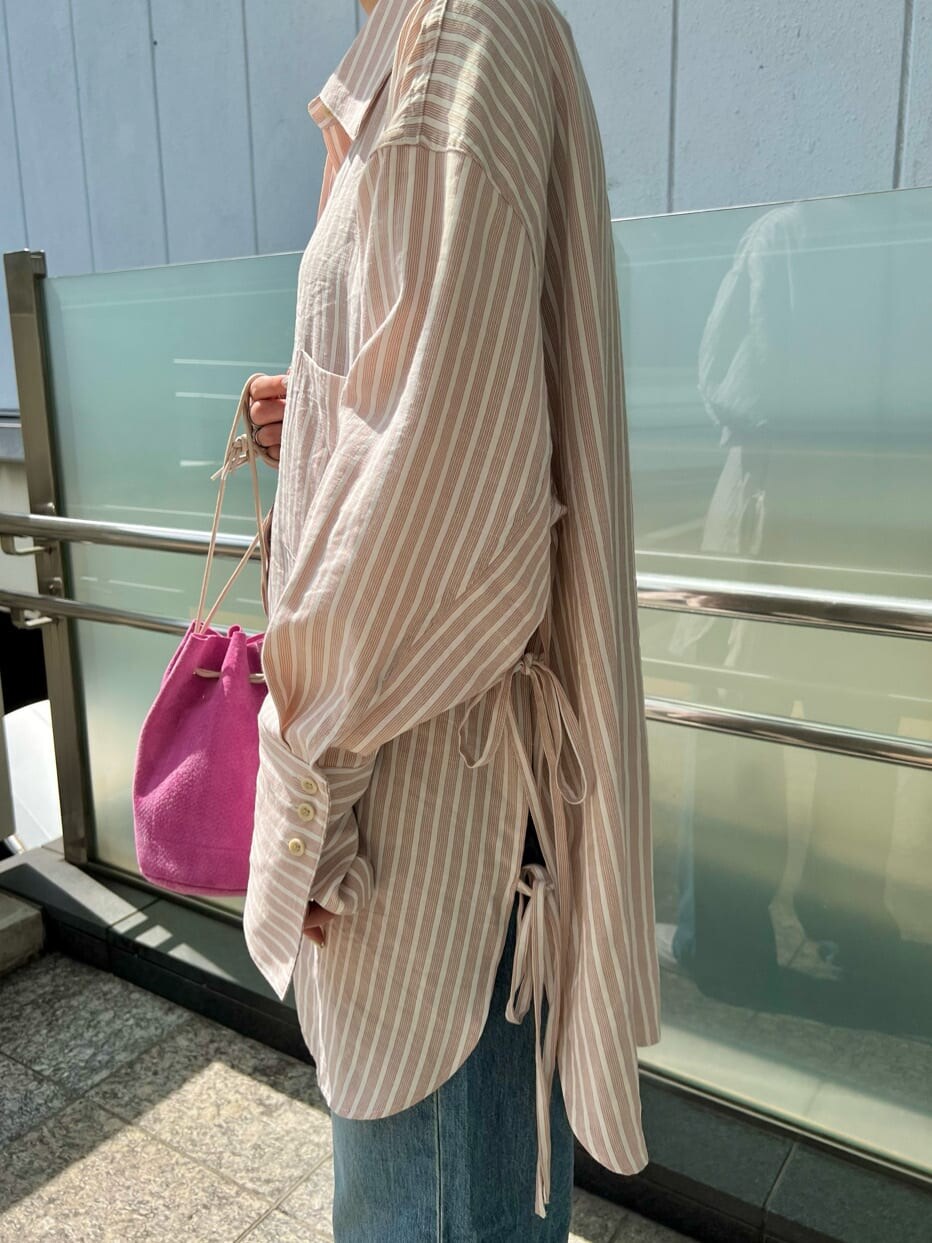 ピンク系のシャツ/ブラウス、ピンク系のハンドバッグ、ブルー系のデニムパンツを着用したレディースの春コーディネートの6枚目の写真