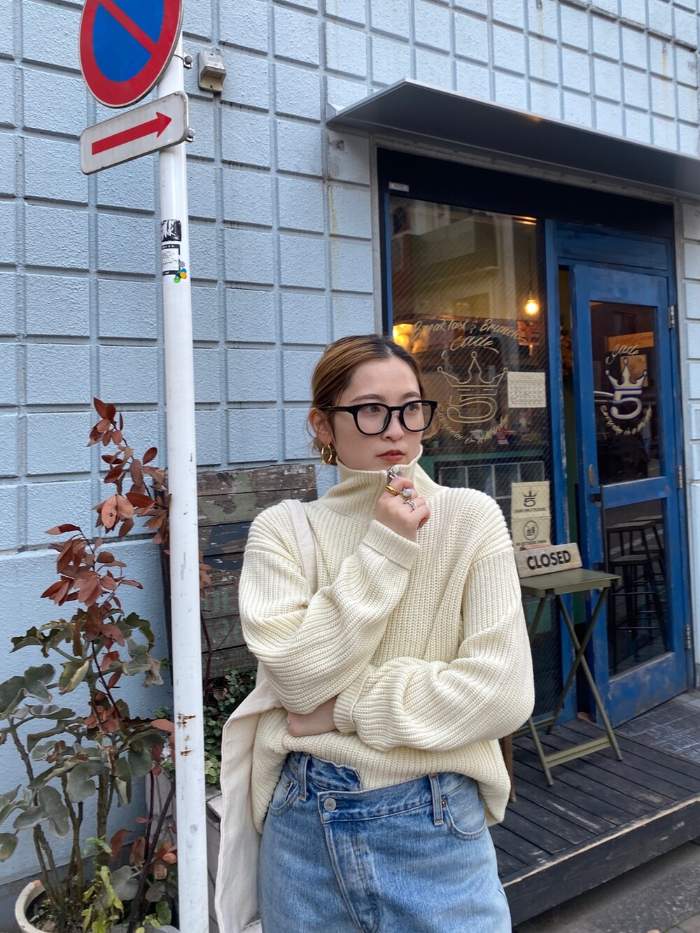 ホワイト系のニット/セーター、ブルー系のデニムパンツ、レッド系のトートバッグを着用したレディースの冬コーディネートの2枚目の写真