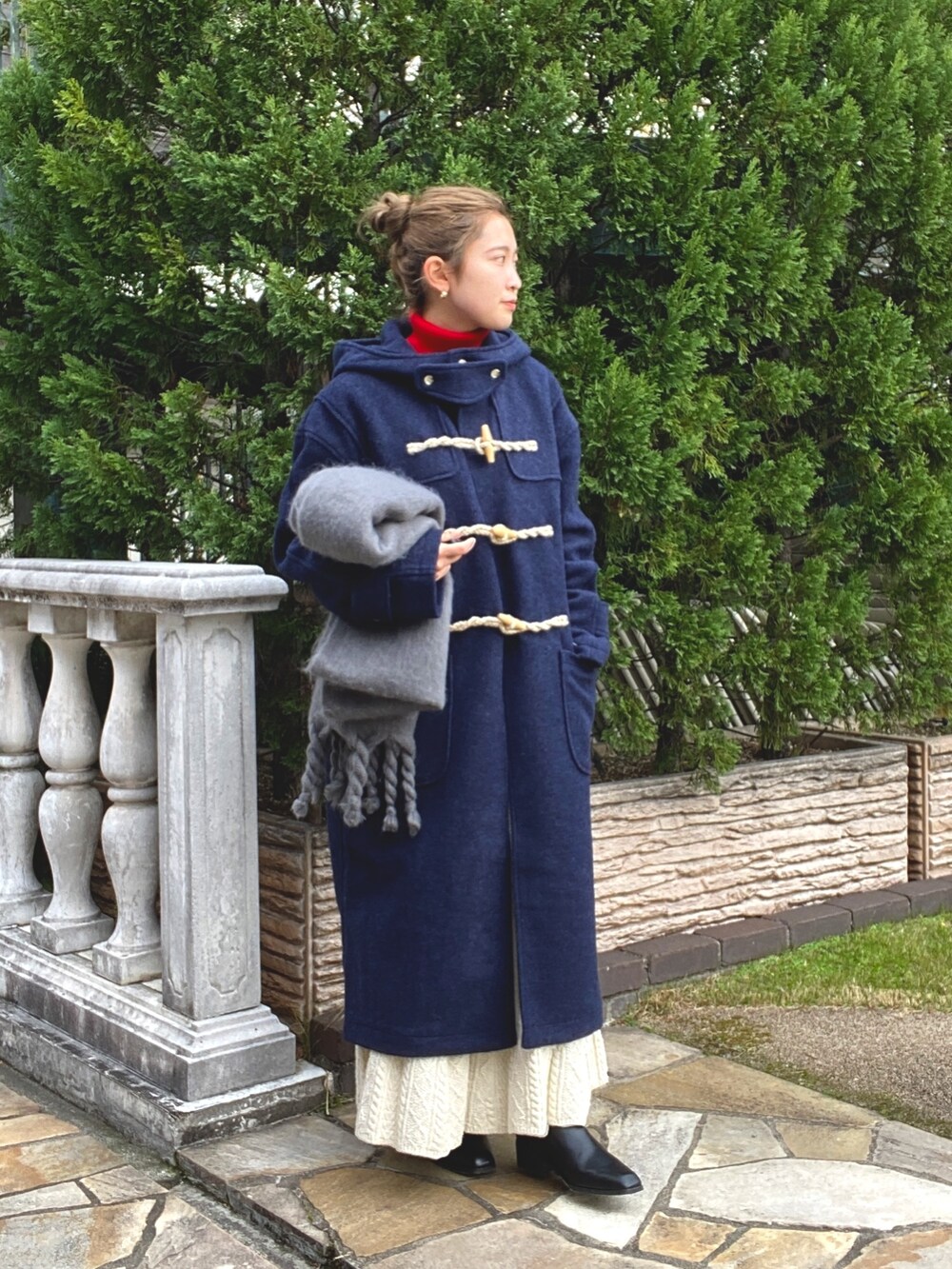 ホワイト系のスカート、ブルー系のダッフルコート、レッド系のニット/セーターを着用したレディースの冬コーディネートの2枚目の写真