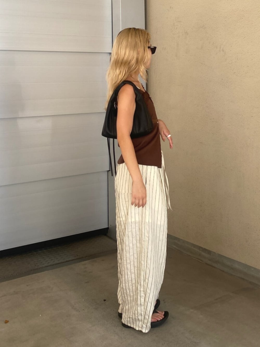 ホワイト系のその他パンツ、ブラウン系のTシャツ/カットソー、ブラック系のハンドバッグを着用したレディースの夏コーディネートの2枚目の写真
