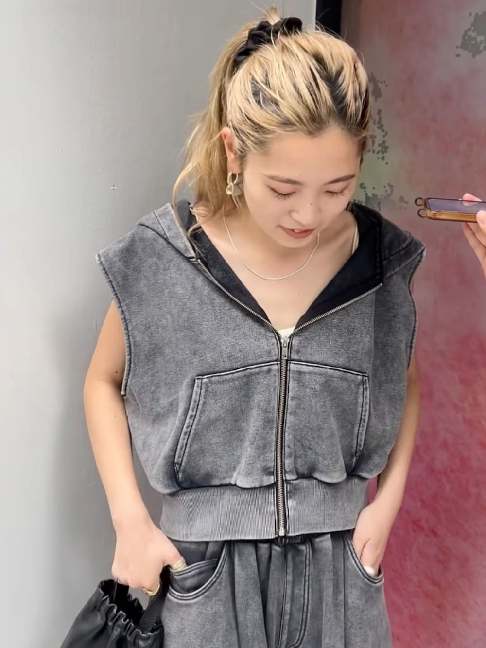 グレー系のパーカー、グレー系のスウェットパンツ、ブラック系のショルダーバッグを着用したレディースの夏コーディネートの3枚目の写真