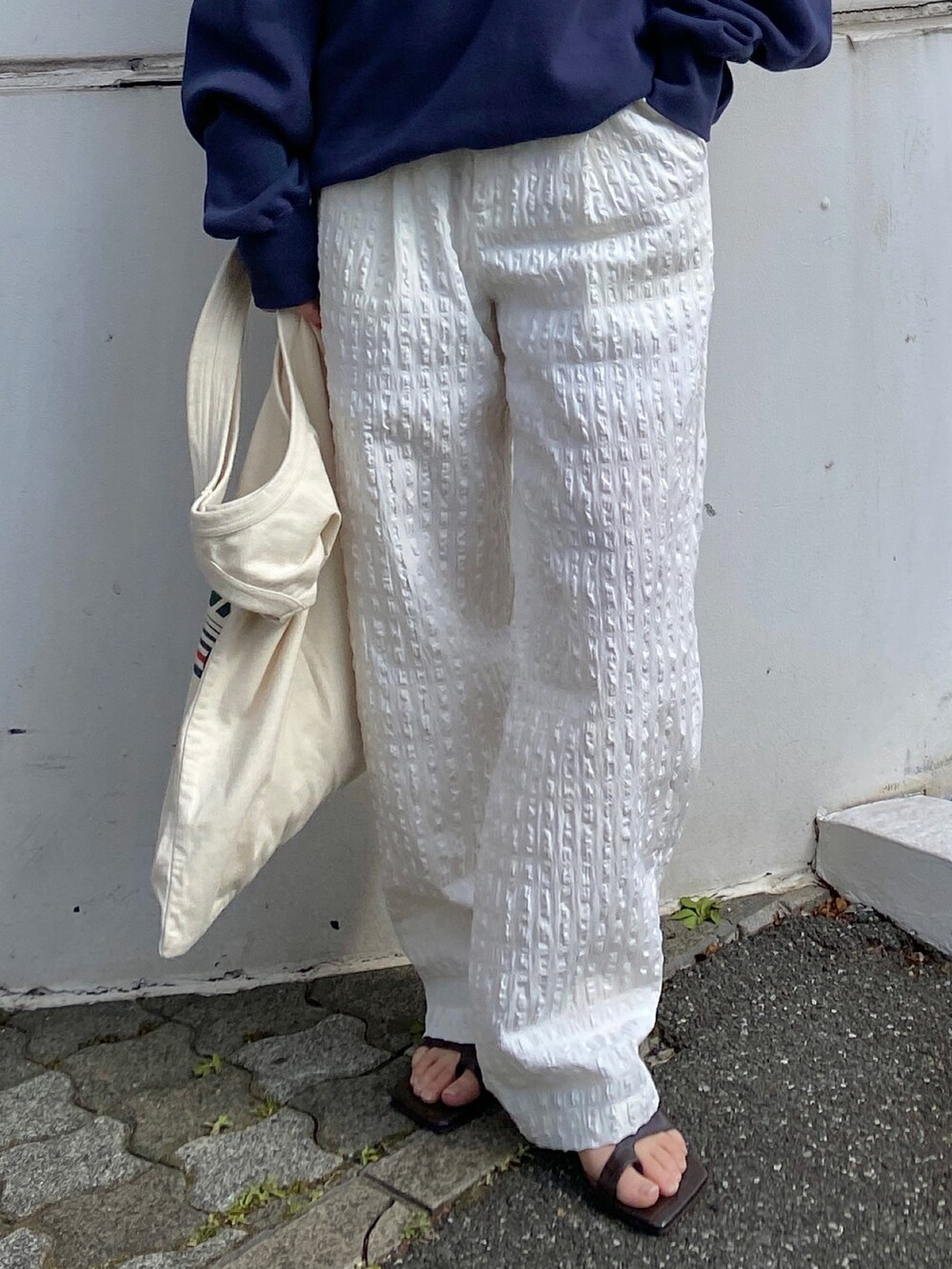 ブルー系のスウェット、ホワイト系のその他パンツ、グリーン系のトートバッグを着用したレディースの冬コーディネートの4枚目の写真