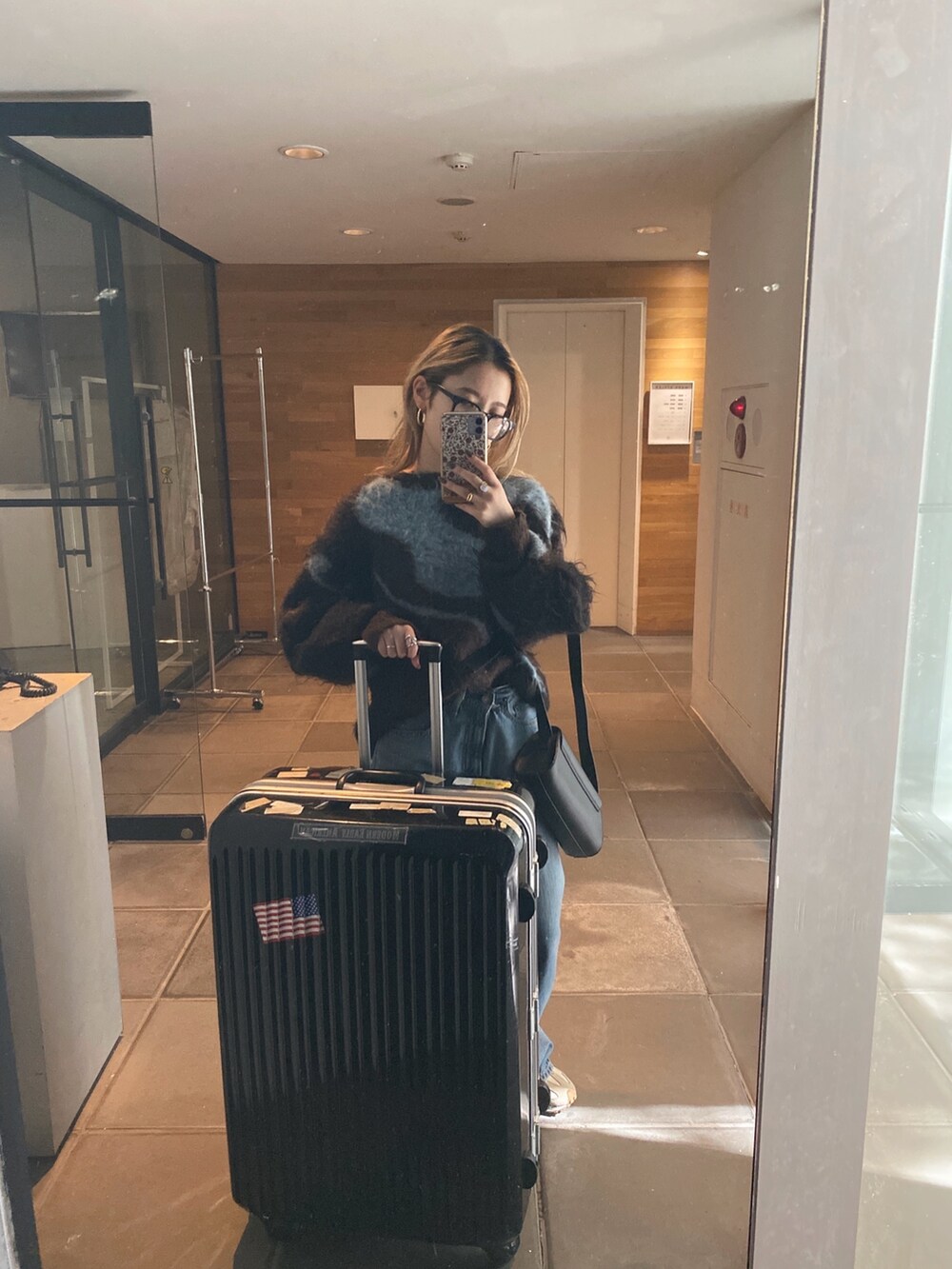 ブラウン系のニット/セーター、ブルー系のデニムパンツ、ブラック系のメガネを着用したレディースの秋コーディネートの4枚目の写真