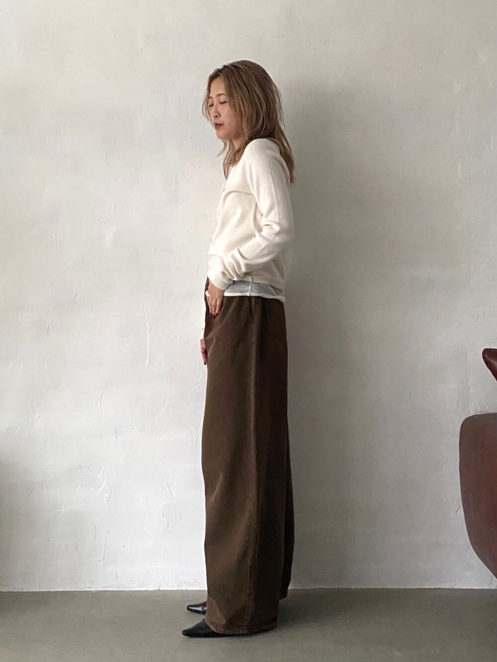ブラック系のパンプス、ブラウン系のデニムパンツ、ホワイト系のニット/セーターを着用したレディースの秋コーディネートの2枚目の写真