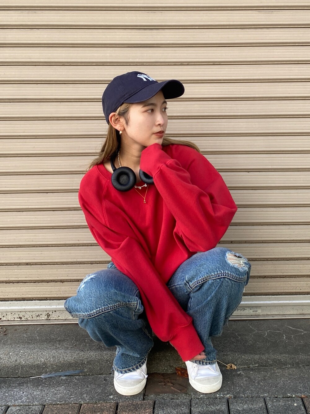 レッド系のニット/セーター、ブルー系のデニムパンツを着用したレディースの秋コーディネートの2枚目の写真