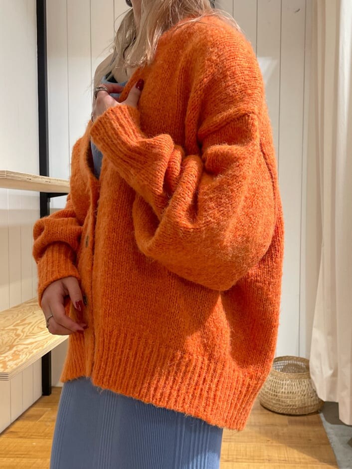 オレンジ系のカーディガン/ボレロ、ブラック系のブーツ、ブルー系のワンピースを着用したレディースの秋コーディネートの7枚目の写真